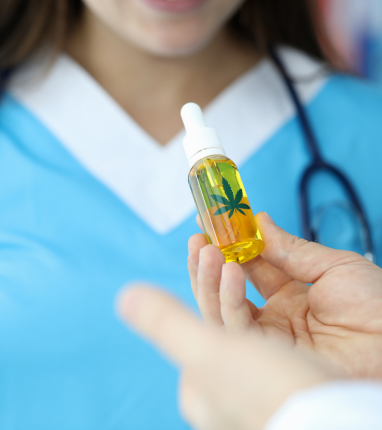 Vial with cannabis leaf image on it held in front of a medical professional