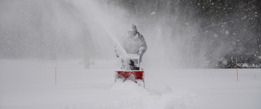 person snowblowing during storm