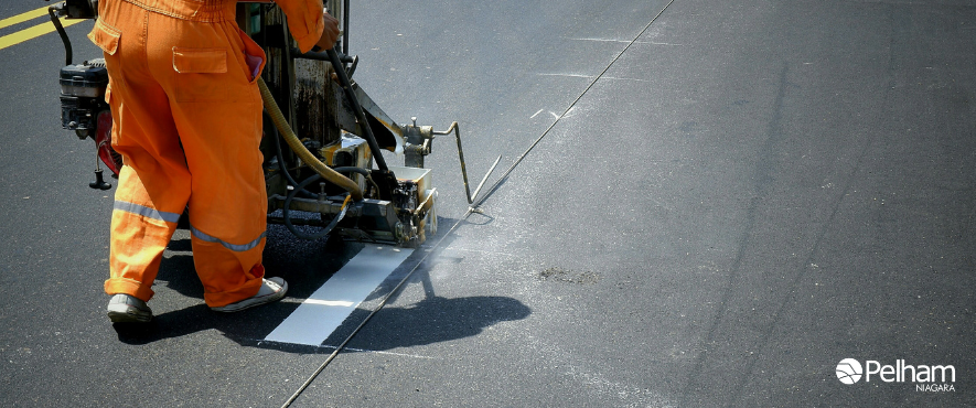 construction worker painting lines on pavement