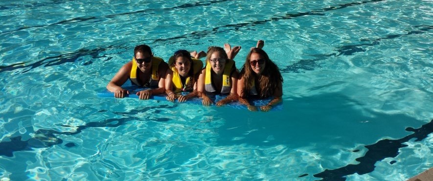 four life guards in pool on flotation device