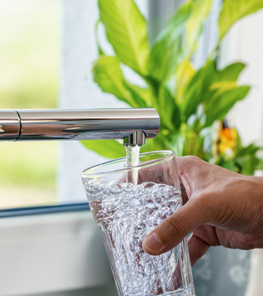 person filling glass from faucet